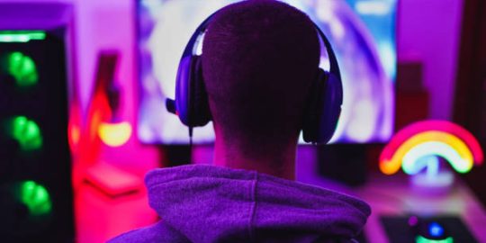 Young man wearing headset and play computer video games online - Home isolated for coronavirus outbreak